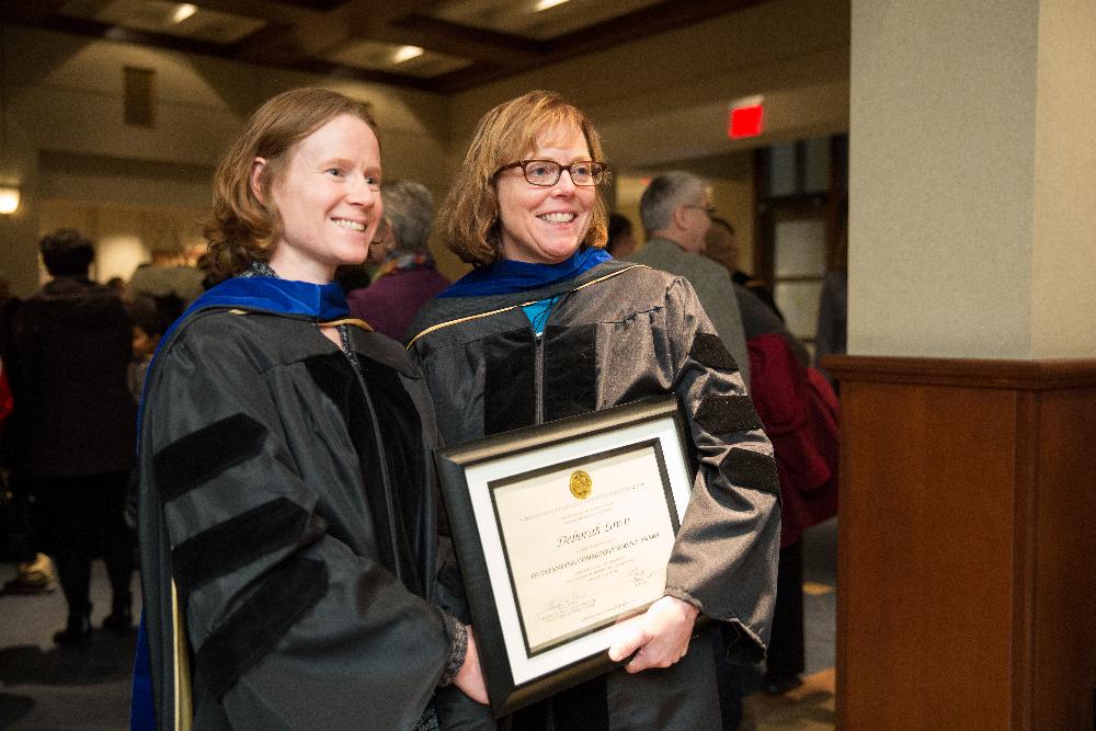 Two members of faculty pose for a picture with an award